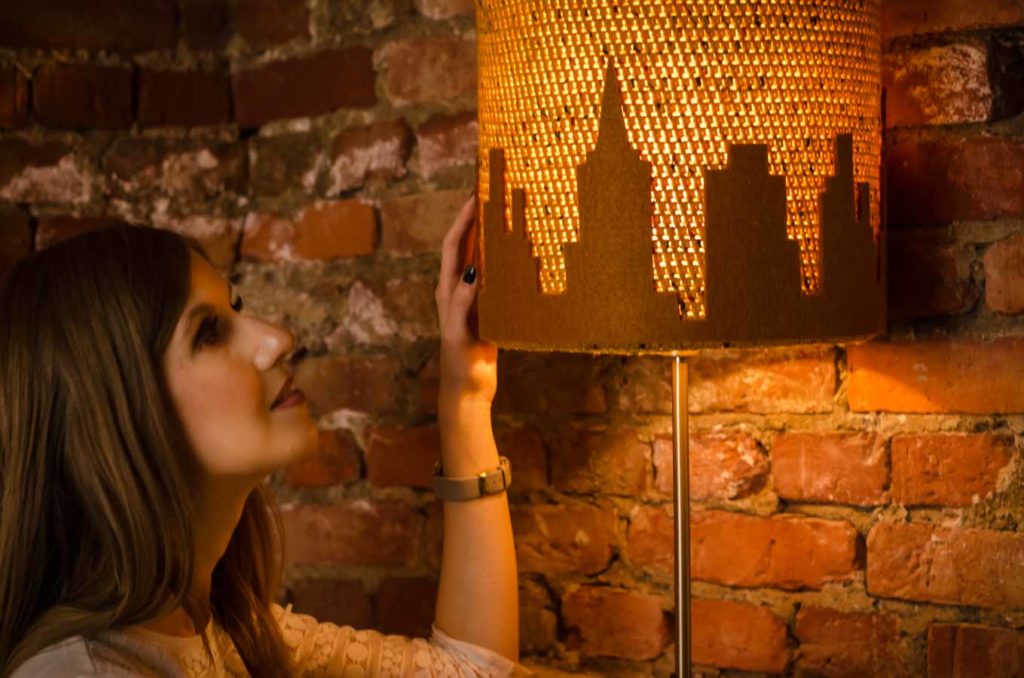 Kobieta delikatnie dotyka abażur od lampy